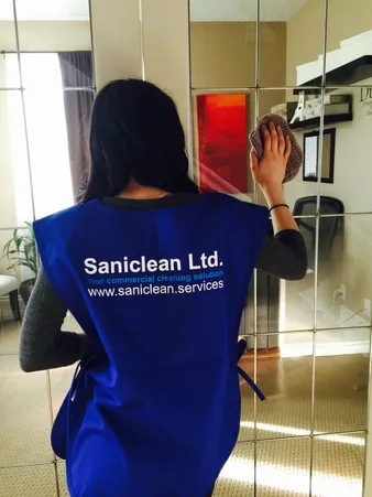 Saniclean employee cleaning a mirror